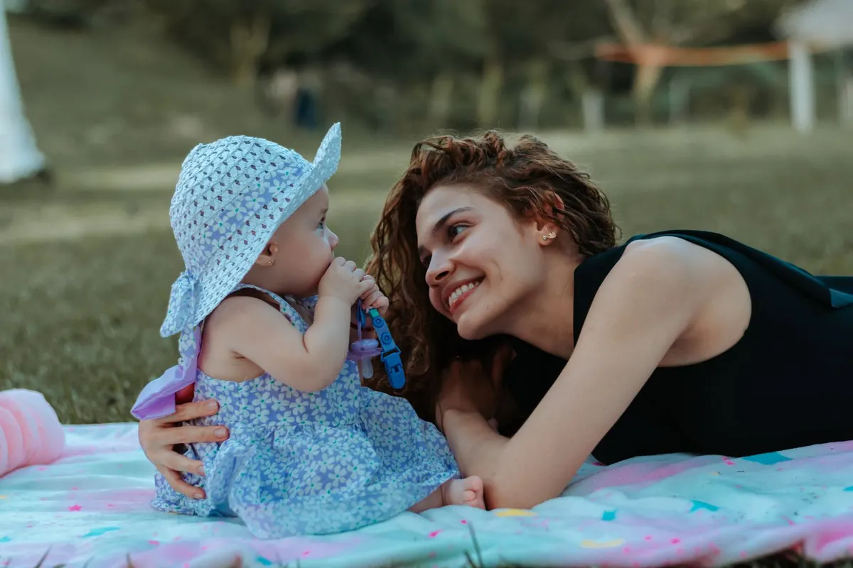 A mother and her baby relaxing together on a picnic blanket