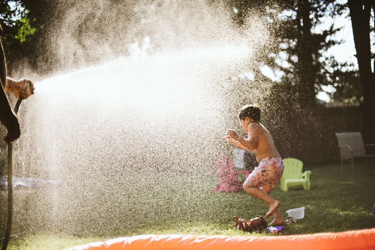 A child playing under a garden sprinkler on a summer afternoon