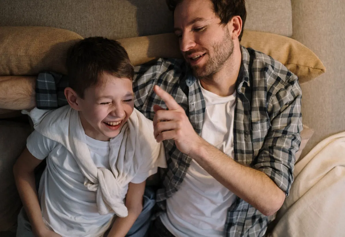 A dad and his son laughing together on the couch