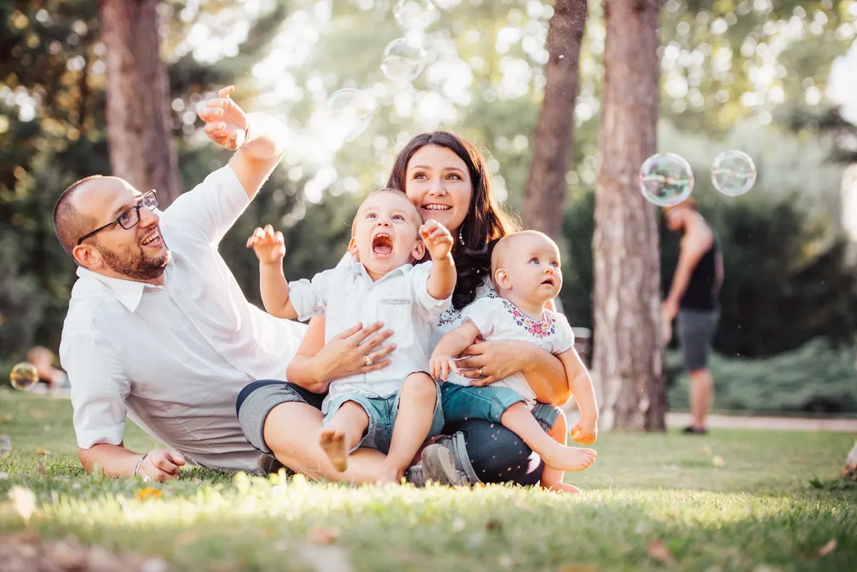 A family playing together on the grass in a sunny park