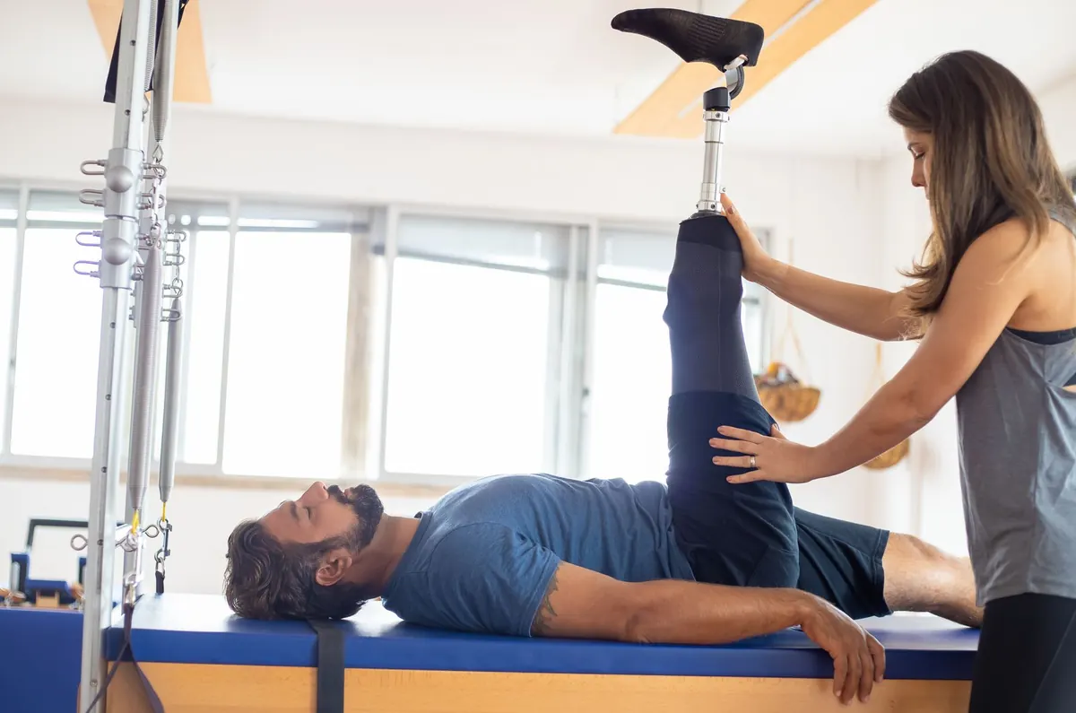 A physiotherapist helping a man with a prosthetic leg through his rehab